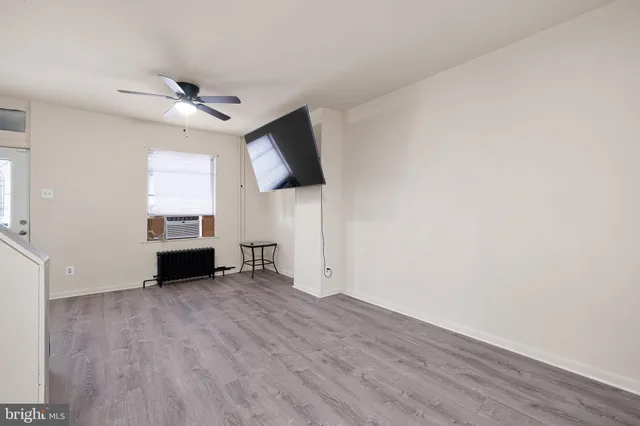 a view of an empty room with a window and wooden floor