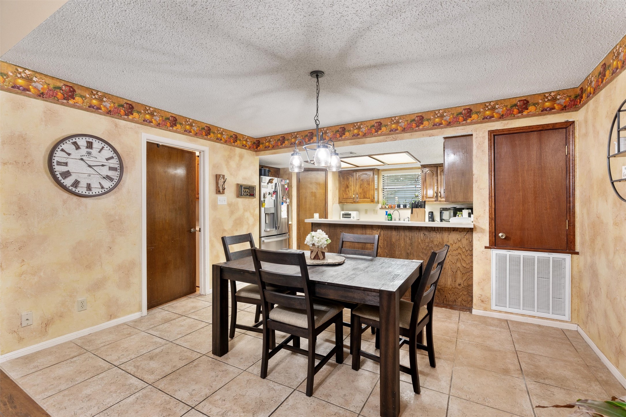 401 Drake Lane Taylor, TX 76574 - Photo 8 of 31 Dining area featuring tile flooring, a textured ceiling, and a pass-through opening to the kitchen