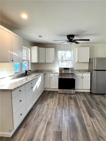 a large kitchen with granite countertop a stove top oven a sink dishwasher and a refrigerator