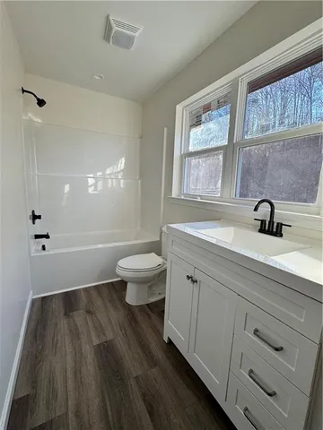 a bathroom with a sink a toilet a window and shower