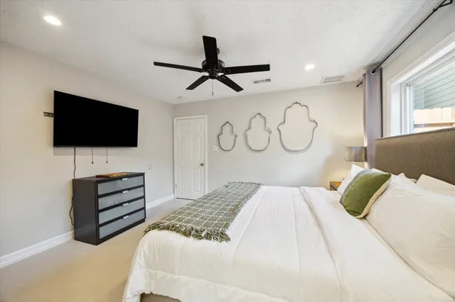 a bedroom with a bed a flat screen tv and a window