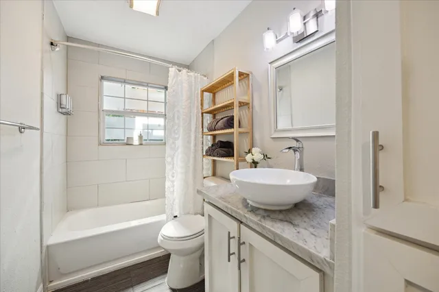 a bathroom with a granite countertop sink a toilet a mirror and bathtub