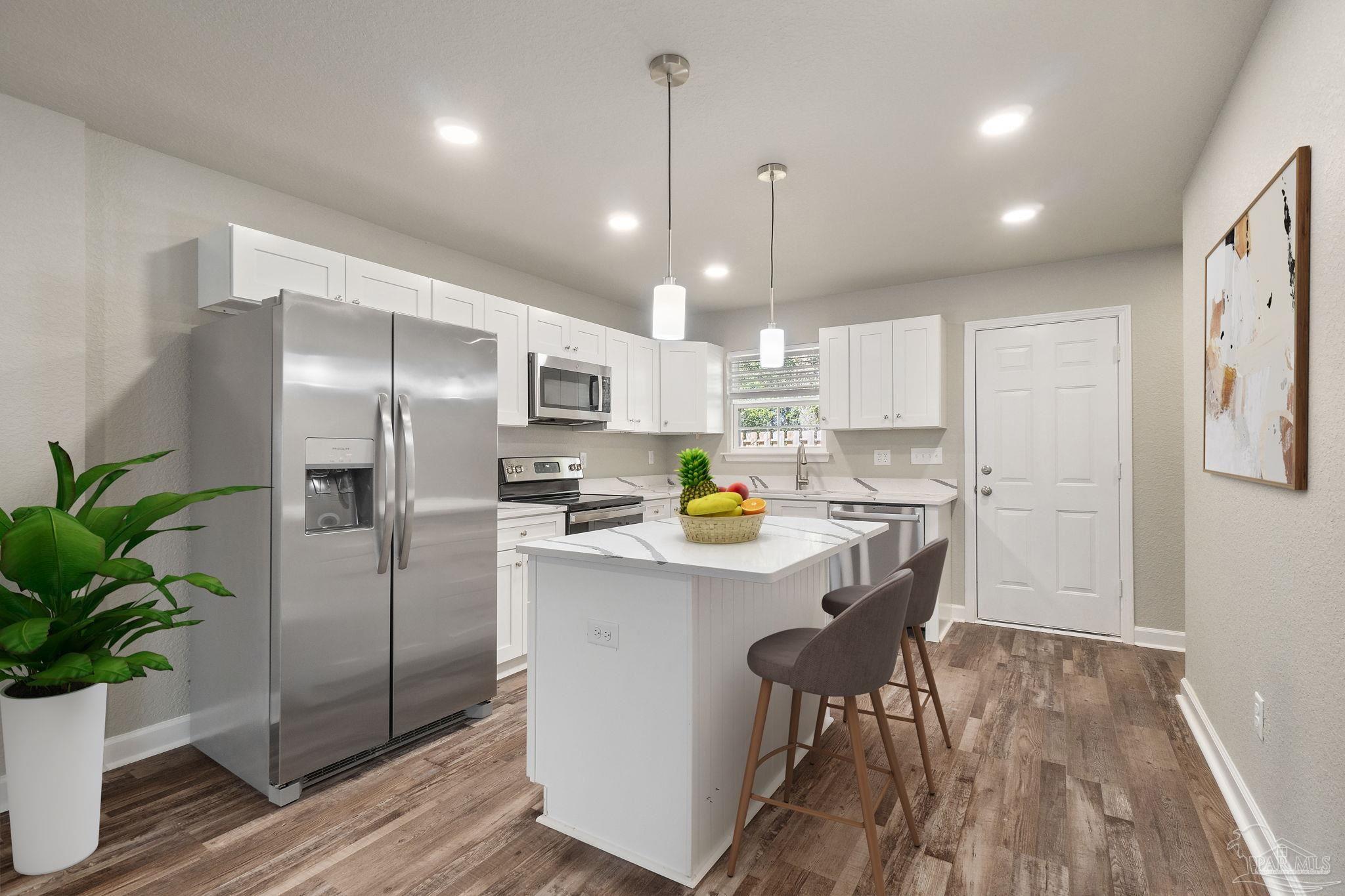 9906 Holsberry Road, Unit 101 Pensacola, FL 32534 - Photo 4 of 16 a kitchen with stainless steel appliances a refrigerator a sink a stove a dining table and chairs