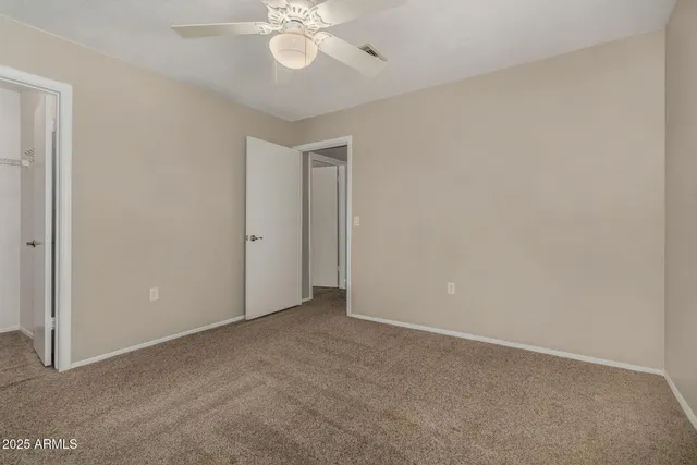 a view of an empty room with a chandelier fan