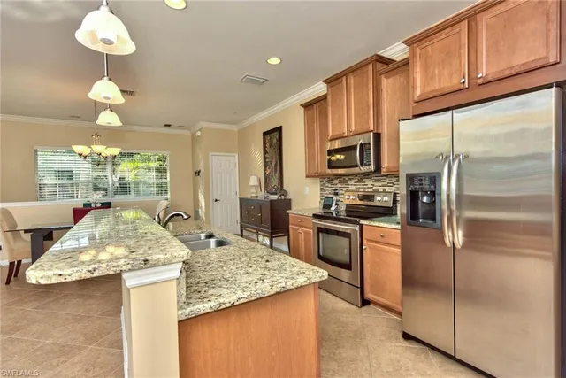 a kitchen with kitchen island granite countertop stainless steel appliances and a refrigerator