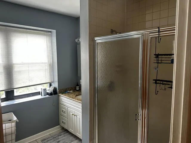 a bathroom with a granite countertop sink and a shower