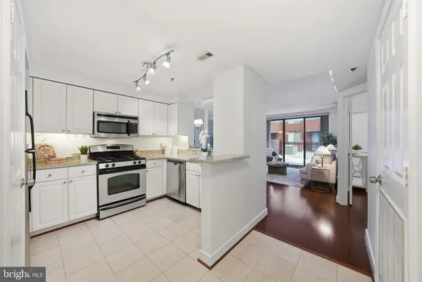 a kitchen with stainless steel appliances granite countertop a refrigerator stove microwave and white cabinets