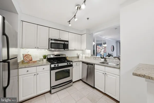 a kitchen with granite countertop white cabinets stainless steel appliances and sink