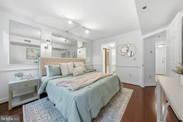 a spacious bedroom with a bed and a lamp on a dresser