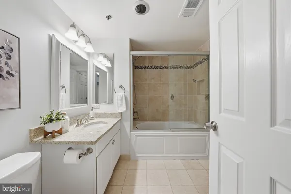 a bathroom with a granite countertop sink mirror and a bathtub