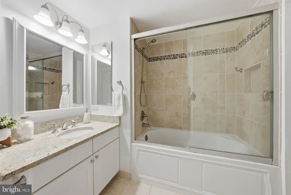 a bathroom with a granite countertop sink a mirror a bathtub and shower