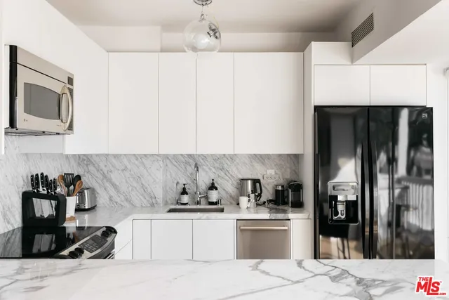 a kitchen with stainless steel appliances kitchen island granite countertop a refrigerator and a sink