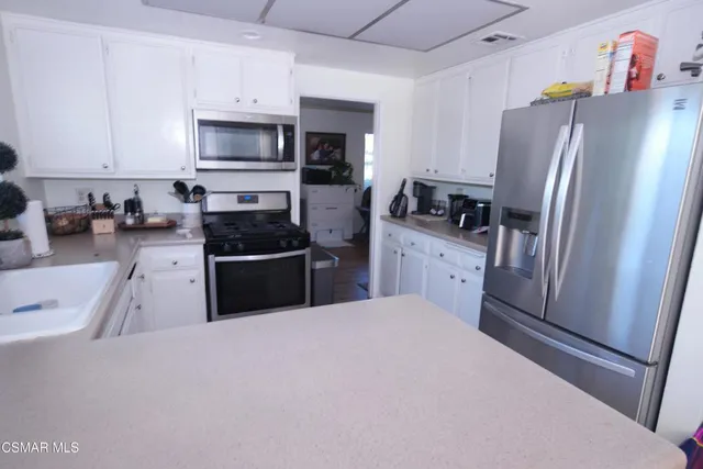 a kitchen with granite countertop a refrigerator a sink a stove a microwave and cabinets