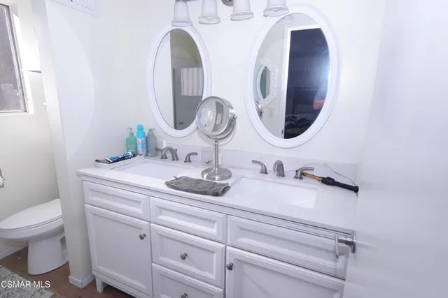 a bathroom with a granite countertop toilet sink and mirror