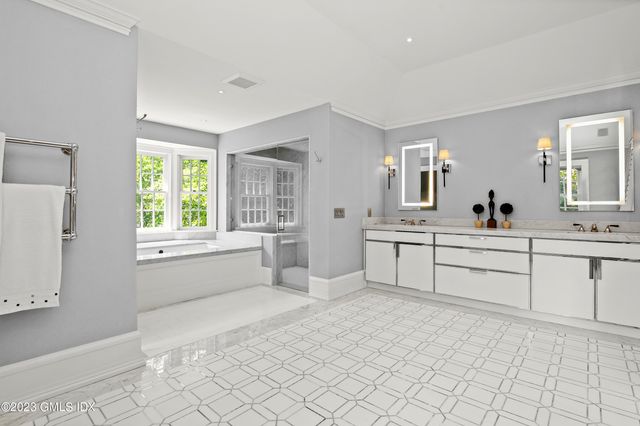 a large white bathroom with a window sink and mirror