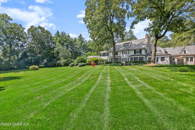 a view of a house with a big yard and large trees