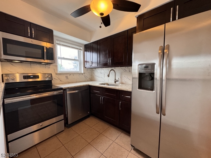 a kitchen with stainless steel appliances granite countertop a refrigerator a sink a stove and microwave