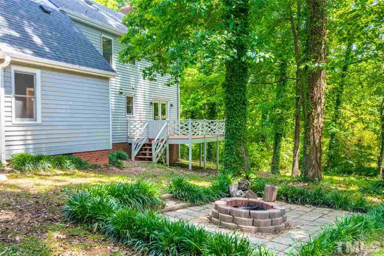 Large hardwood trees surrounding the backyard firepit.