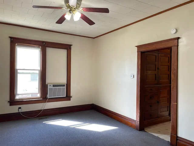 an empty room with windows and fan