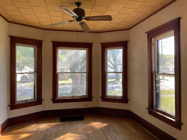 a view of an empty room with a window and wooden floor