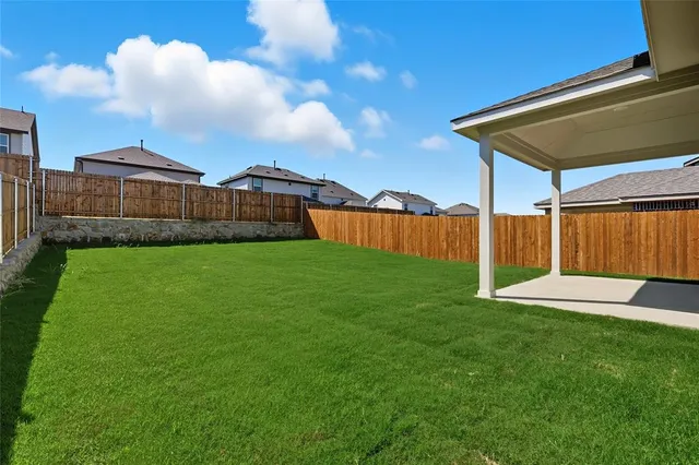 a view of a backyard with a barbeque and wooden fence