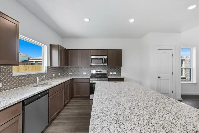 a large kitchen with stainless steel appliances granite countertop a sink stove and cabinets