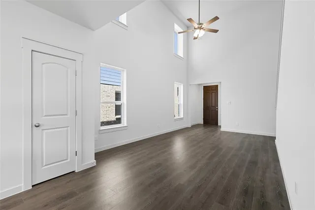 an empty room with wooden floor ceiling fan and windows