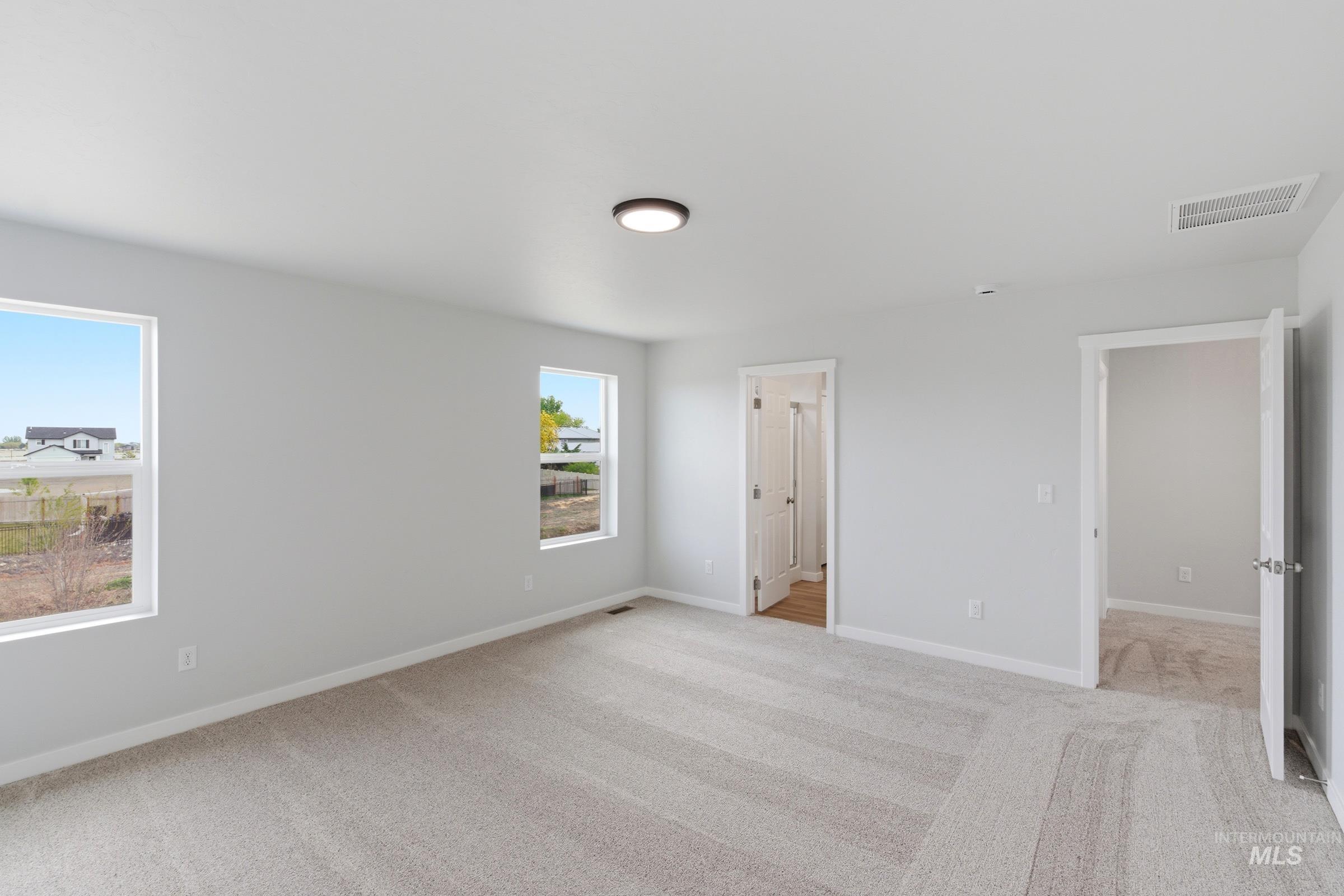 16558 Dunning Way Caldwell, ID 83607 - Photo 25 of 35 Spacious room featuring light gray carpeting, two windows, two entryways, and a ceiling-mounted light fixture