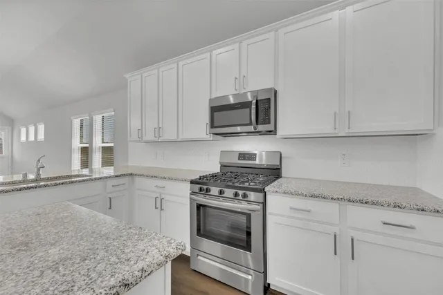 a kitchen with granite countertop white cabinets and stainless steel appliances