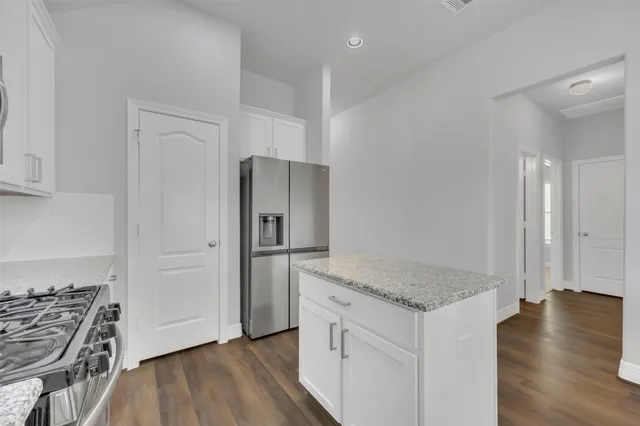 a kitchen with granite countertop a refrigerator and a stove top oven
