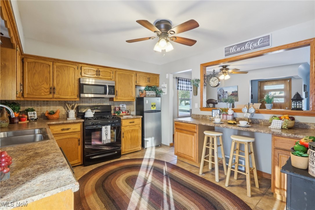 2634 Brunswick Road Youngstown, OH 44511 - Photo 11 of 50 Kitchen with tasteful backsplash, stainless steel appliances, ceiling fan, sink, and light tile patterned floors