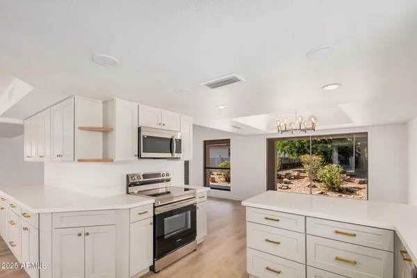 a kitchen with stainless steel appliances white cabinets and a stove top oven