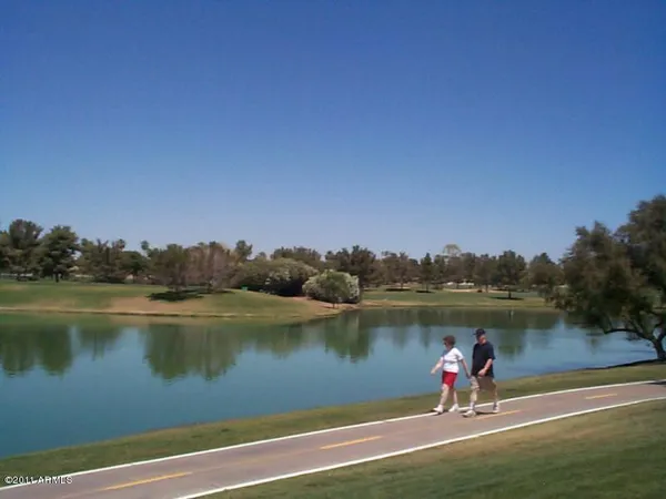 a view of a lake with a yard and a wooden fence