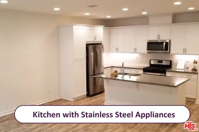 a kitchen with stainless steel appliances granite countertop a sink refrigerator stove and microwave