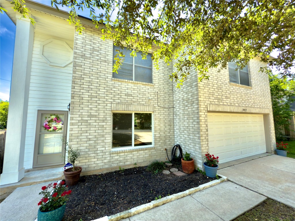 View of front facade featuring a garage, concrete driveway, and brick siding
