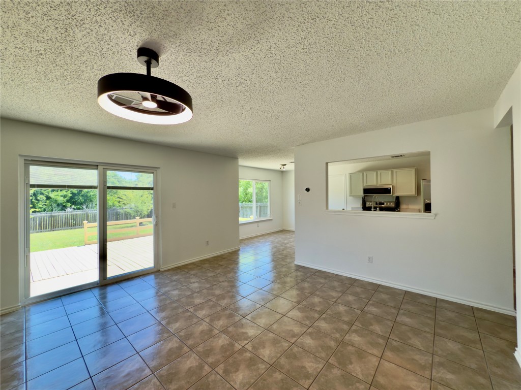 7817 Marble Ridge Drive Austin, TX 78747 - Photo 13 of 38 Unfurnished living room featuring ceiling fan, tile patterned flooring, a textured ceiling, and baseboards