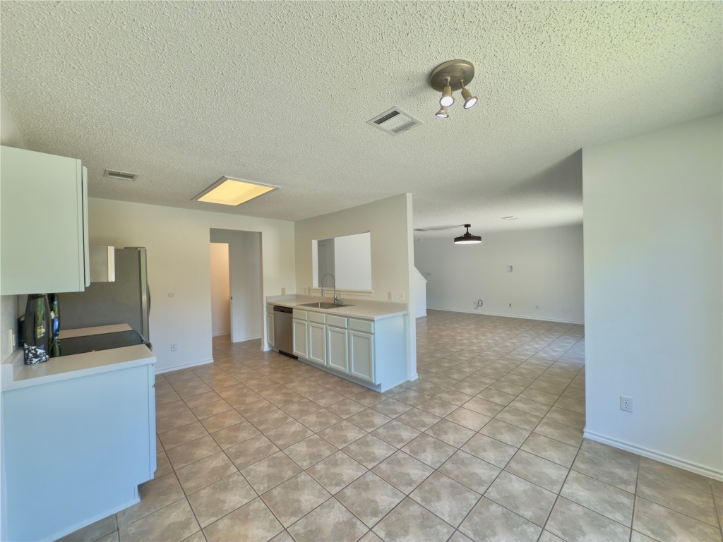 7817 Marble Ridge Drive Austin, TX 78747 - Photo 38 of 38 Kitchen featuring a sink, stainless steel appliances, open floor plan, light countertops, and a textured ceiling