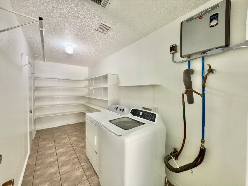 7817 Marble Ridge Drive Austin, TX 78747 - Photo 21 of 38 Laundry area with washing machine and dryer, a textured ceiling, and light tile patterned floors