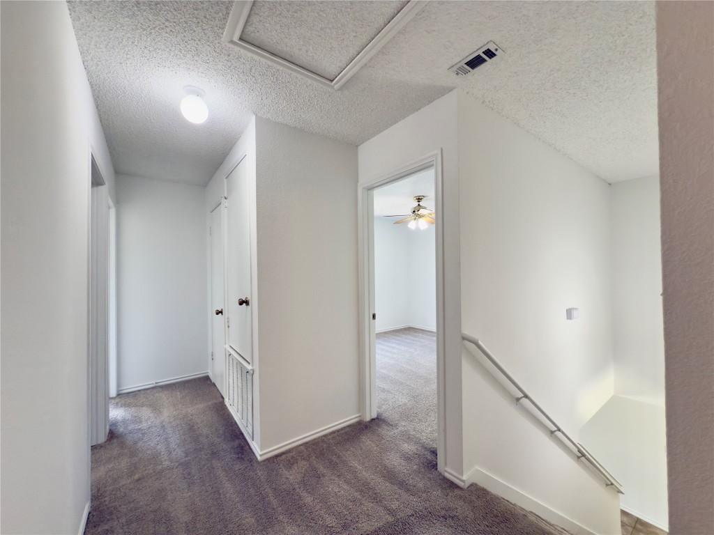 7817 Marble Ridge Drive Austin, TX 78747 - Photo 22 of 38 Corridor featuring an upstairs landing, carpet floors, a textured ceiling, and attic access