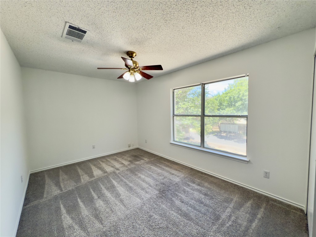 7817 Marble Ridge Drive Austin, TX 78747 - Photo 25 of 38 Spare room featuring carpet floors, a ceiling fan, a textured ceiling, and baseboards