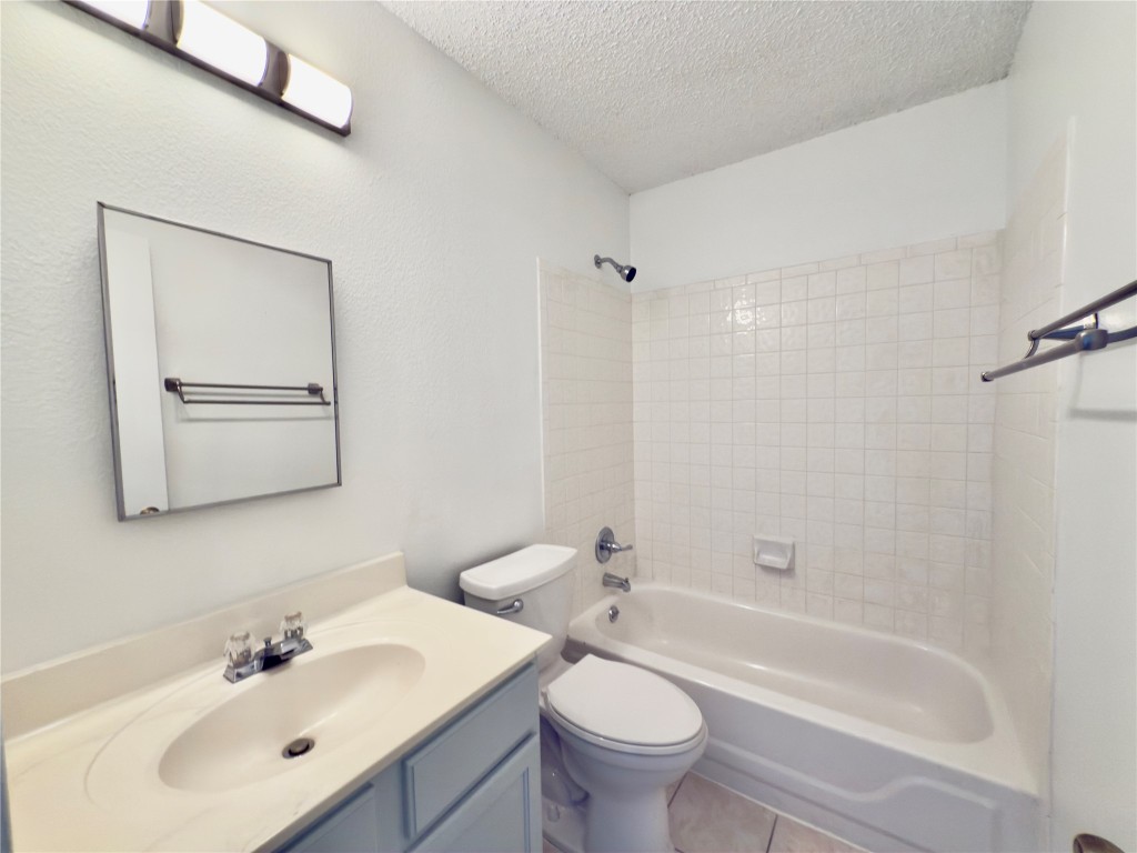 7817 Marble Ridge Drive Austin, TX 78747 - Photo 27 of 38 Full bath featuring a textured ceiling, toilet, vanity, tile patterned flooring, and shower / bathtub combination