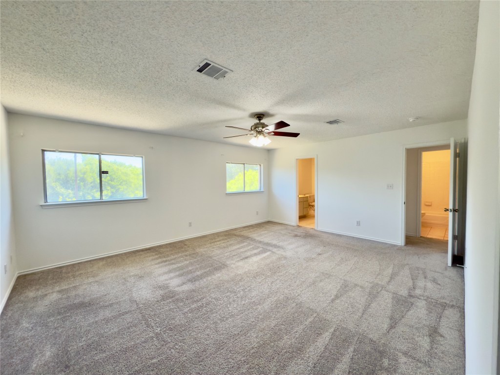 7817 Marble Ridge Drive Austin, TX 78747 - Photo 29 of 38 Empty room with carpet, a ceiling fan, baseboards, and a textured ceiling