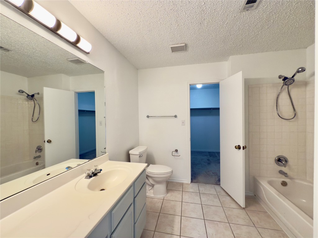 7817 Marble Ridge Drive Austin, TX 78747 - Photo 30 of 38 Full bath with washtub / shower combination, tile patterned floors, a textured ceiling, vanity, and toilet