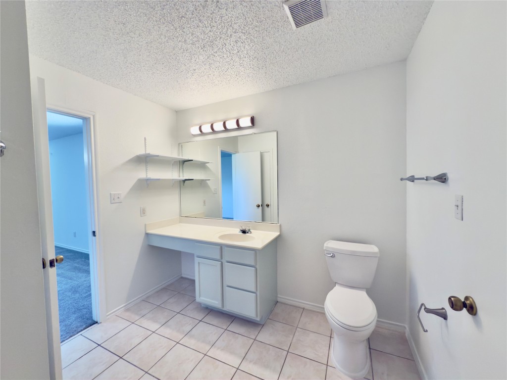 7817 Marble Ridge Drive Austin, TX 78747 - Photo 31 of 38 Half bathroom with a textured ceiling, toilet, vanity, tile patterned flooring, and baseboards