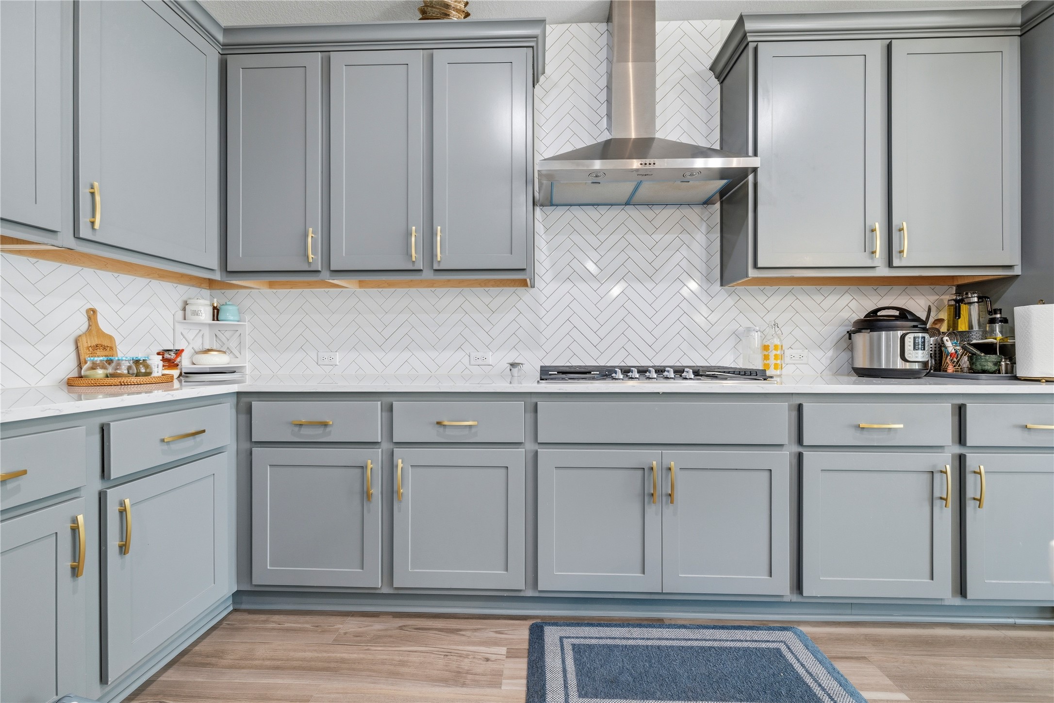 105 Autumn Oak Way Georgetown, TX 78628 - Photo 17 of 40 Kitchen featuring gray cabinetry with gold-toned hardware, white countertops, and a white herringbone tile backsplash