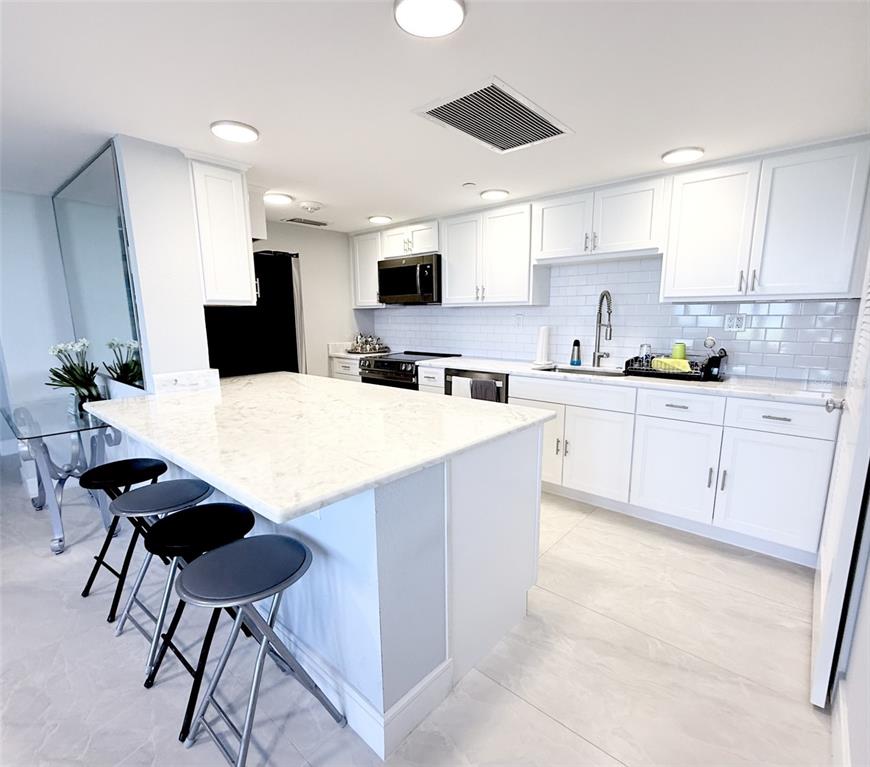 1050 Longboat Club Road, Unit 803 Longboat Key, FL 34228 - Photo 36 of 39 a kitchen with stainless steel appliances kitchen island granite countertop a sink a stove a dining table and chairs