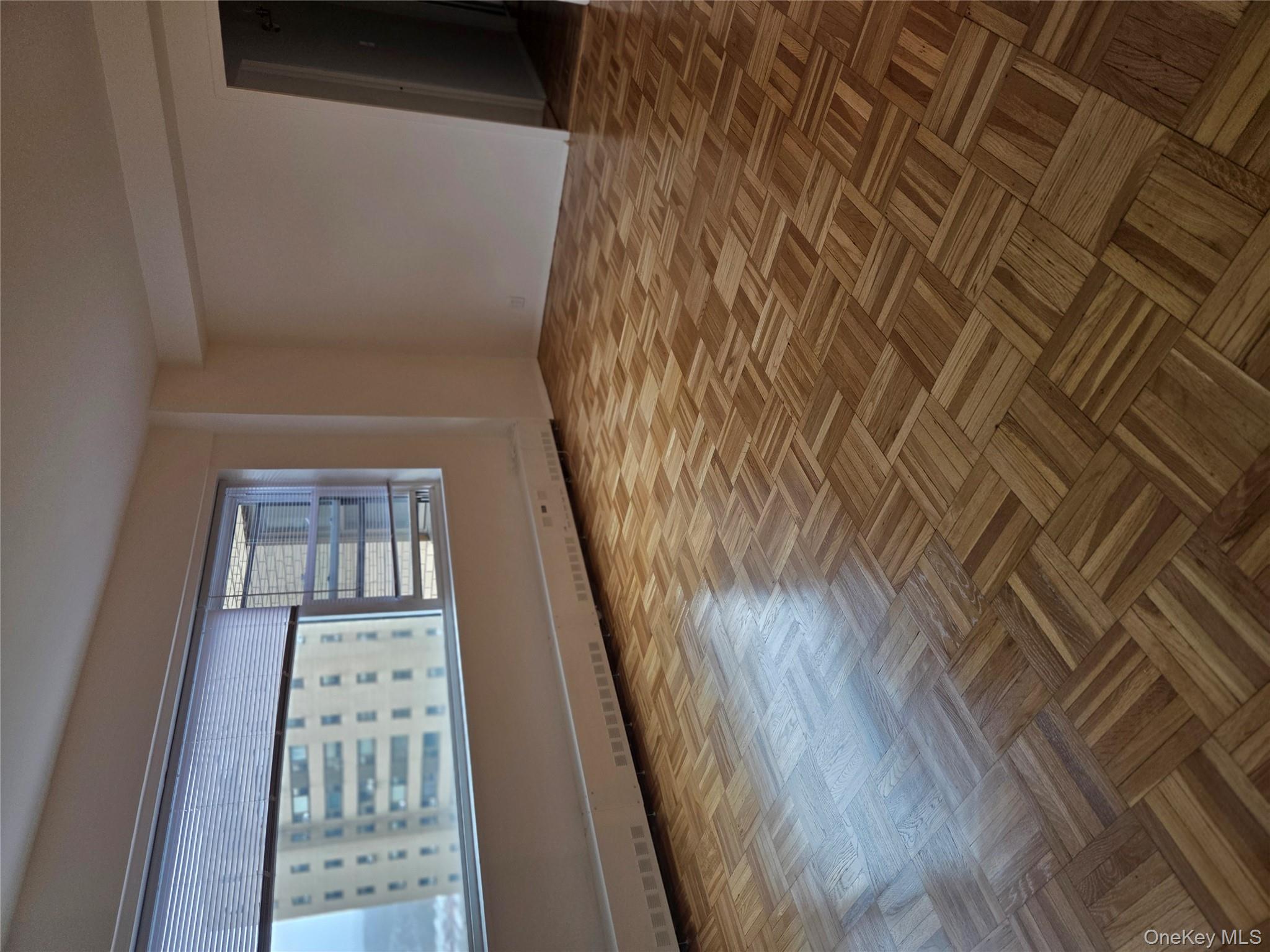 7 Fordham Hill Ovl, Unit 12G Bronx, NY 10468 - Photo 4 of 18 an empty room with wooden floor and windows