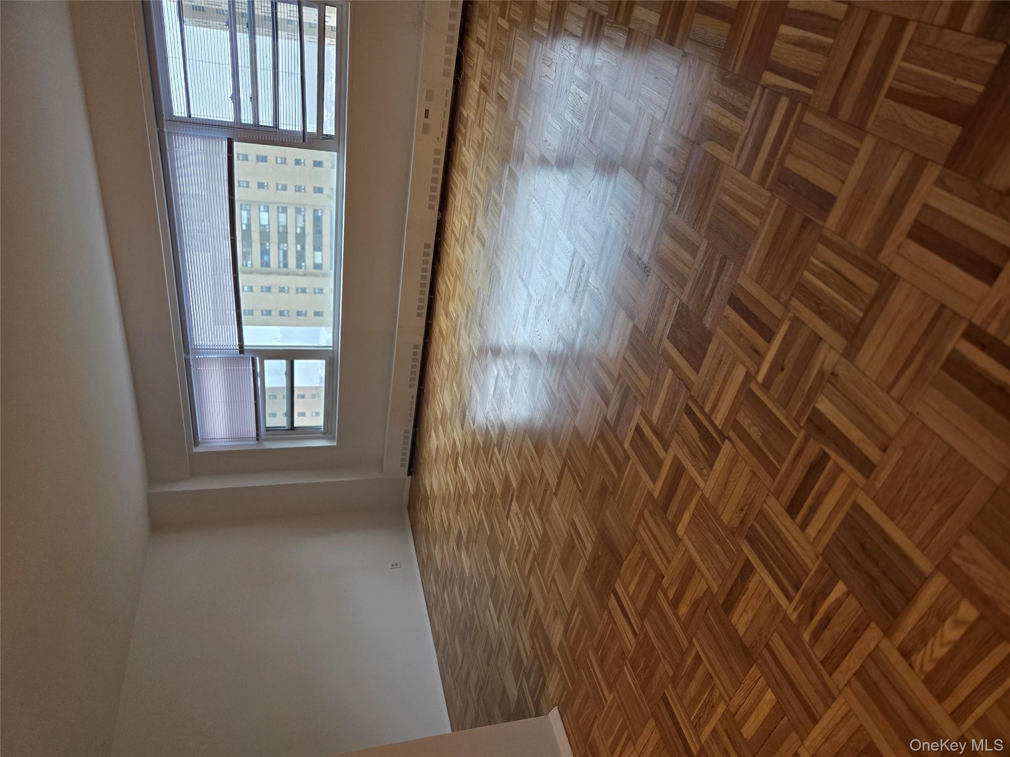 7 Fordham Hill Ovl, Unit 12G Bronx, NY 10468 - Photo 5 of 18 a view of an empty room with wooden floor and a window