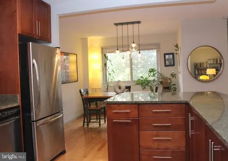 a kitchen with stainless steel appliances granite countertop a refrigerator a stove a sink and a dining table with wooden floor
