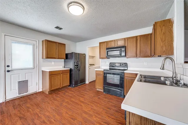 a kitchen with granite countertop a refrigerator stove top oven and sink